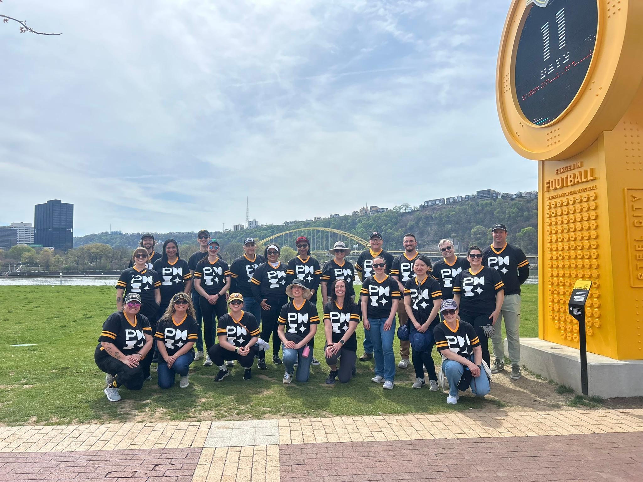 PMI Pittsburgh Volunteers posing next to the countdown clock to the 2026 NFL Draft